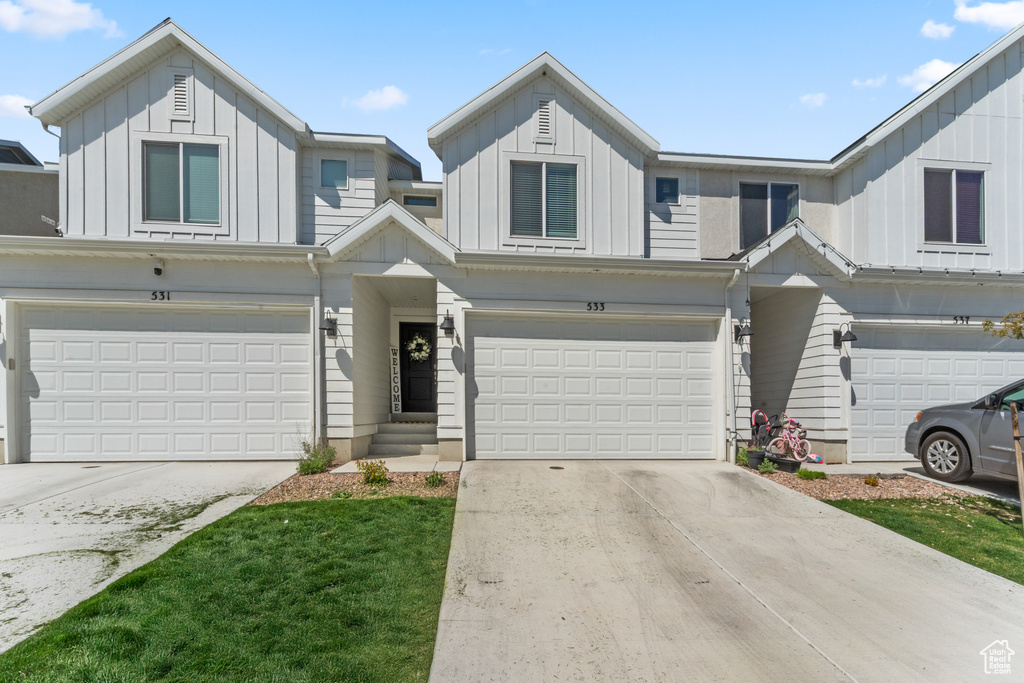 View of property with a garage, board and batten siding, and driveway