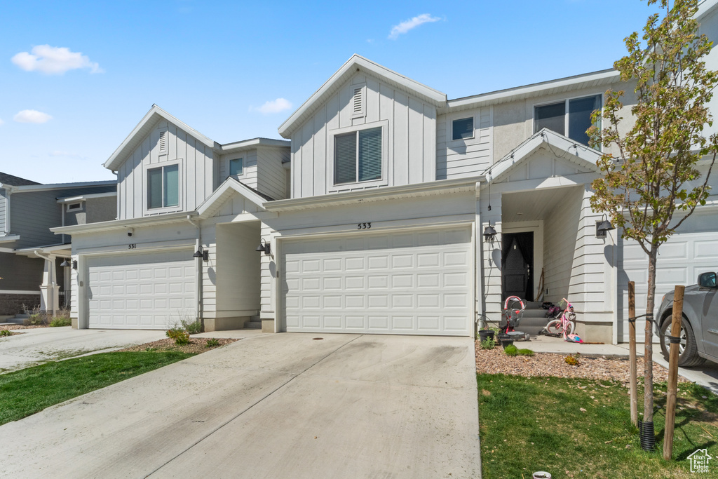 Townhome / multi-family property featuring a garage, board and batten siding, and driveway
