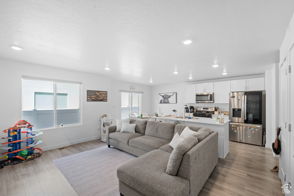 Living area with recessed lighting, light wood finished floors, and baseboards