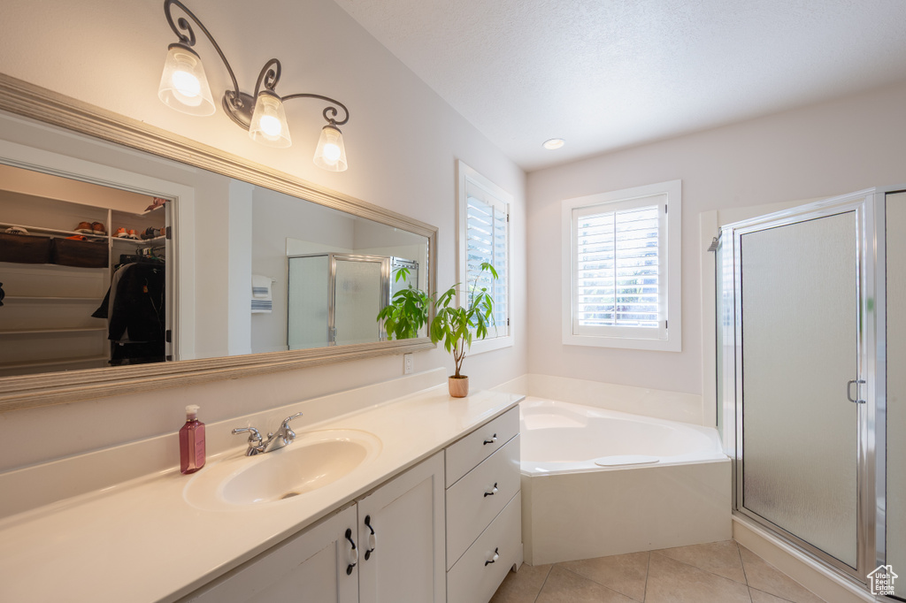Full bathroom with vanity, a bath, a spacious closet, tile patterned floors, and a stall shower
