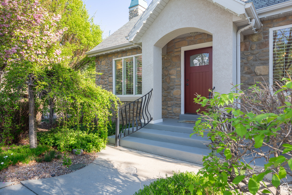 Property entrance with stucco siding, a chimney, and stone siding