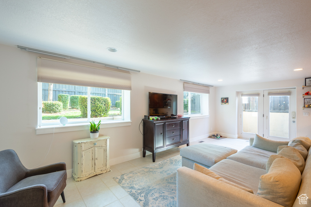 Tiled living area with recessed lighting, a textured ceiling, and baseboards