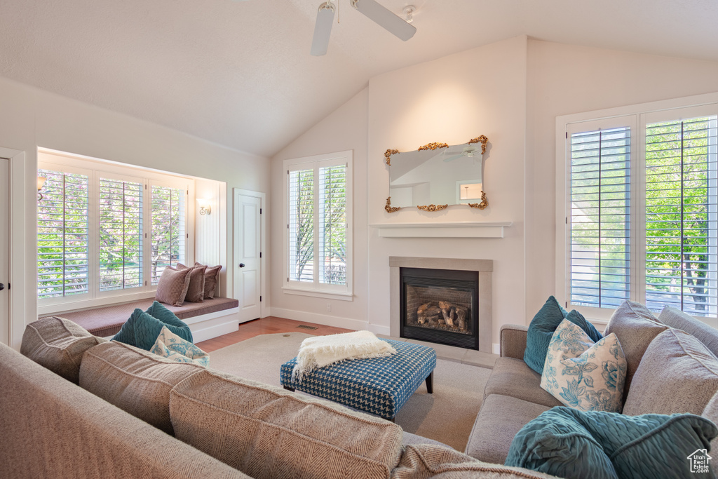 Living room with a glass covered fireplace, baseboards, a ceiling fan, and lofted ceiling