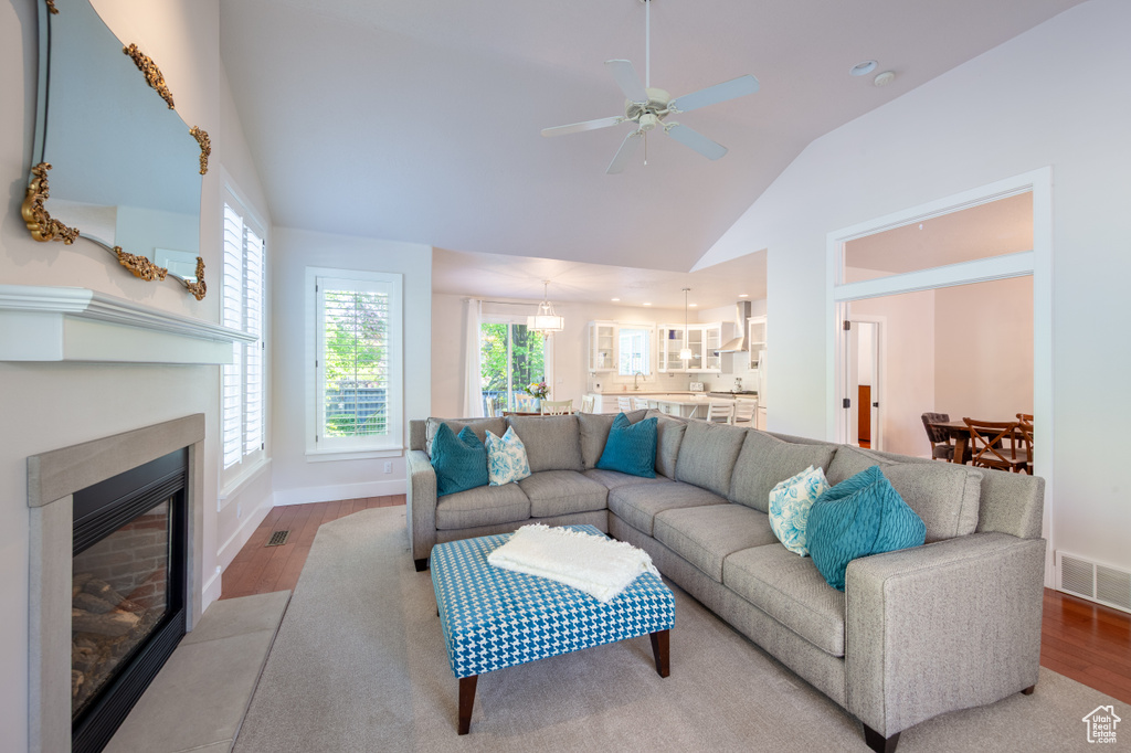 Living room featuring visible vents, a ceiling fan, baseboards, and wood finished floors
