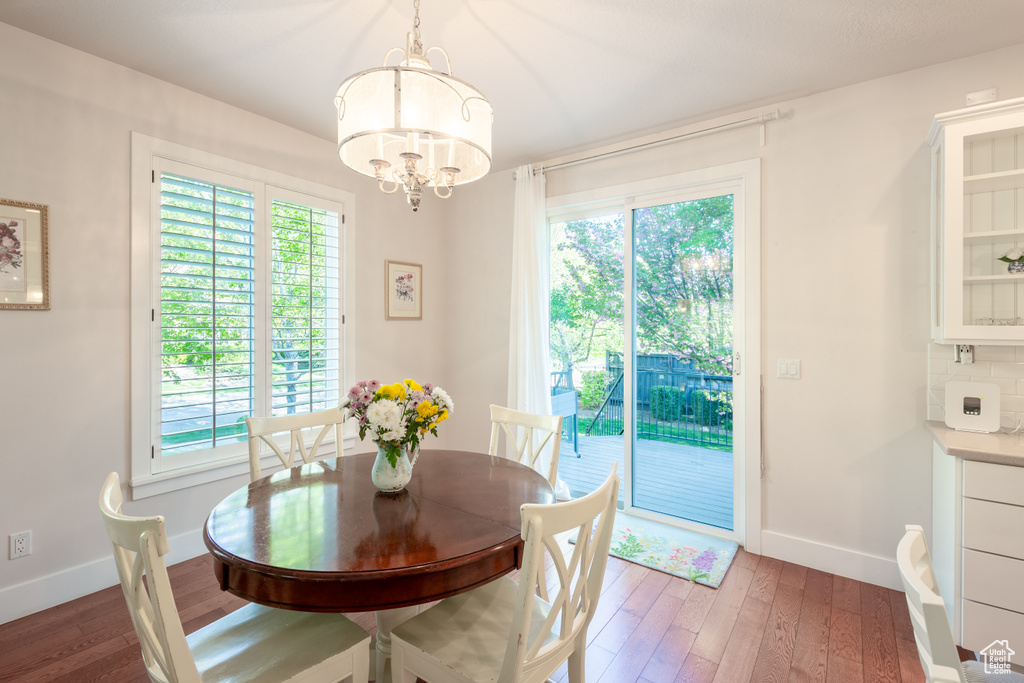Dining room with wood-type flooring, a chandelier, and a wealth of natural light