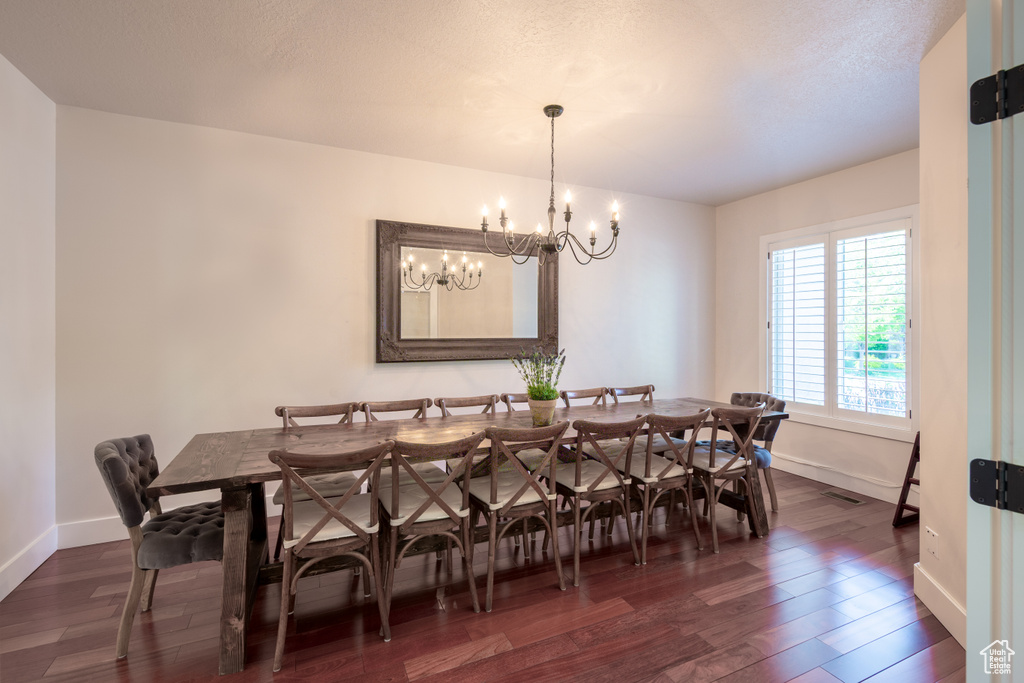 Dining room featuring an inviting chandelier, dark wood finished floors, and baseboards