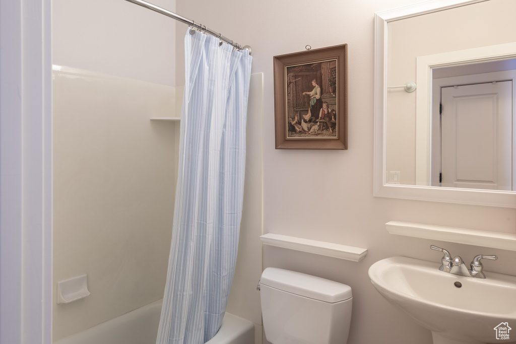 Bathroom with a sink, shower / bath combo with shower curtain, and toilet