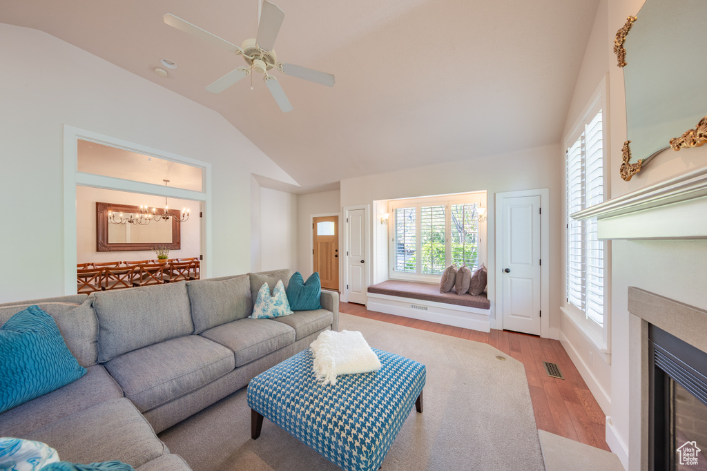 Living area featuring a healthy amount of sunlight, vaulted ceiling, light wood finished floors, and visible vents