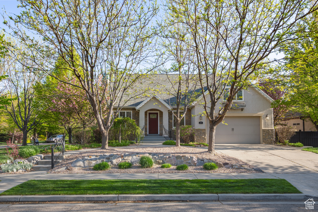 View of front of house featuring a garage, fence, concrete driveway, stone siding, and stucco siding
