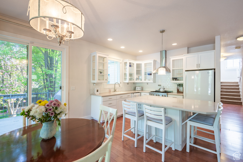 Kitchen with a sink, tasteful backsplash, freestanding refrigerator, and wall chimney exhaust hood
