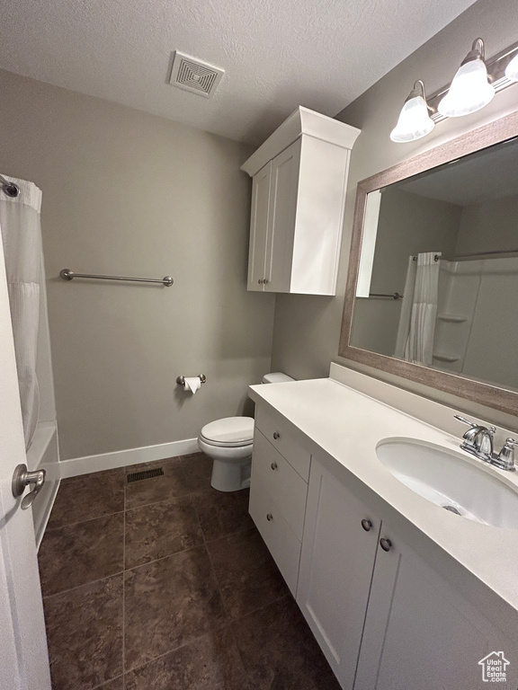 Full bath with vanity, toilet, a textured ceiling, baseboards, and visible vents