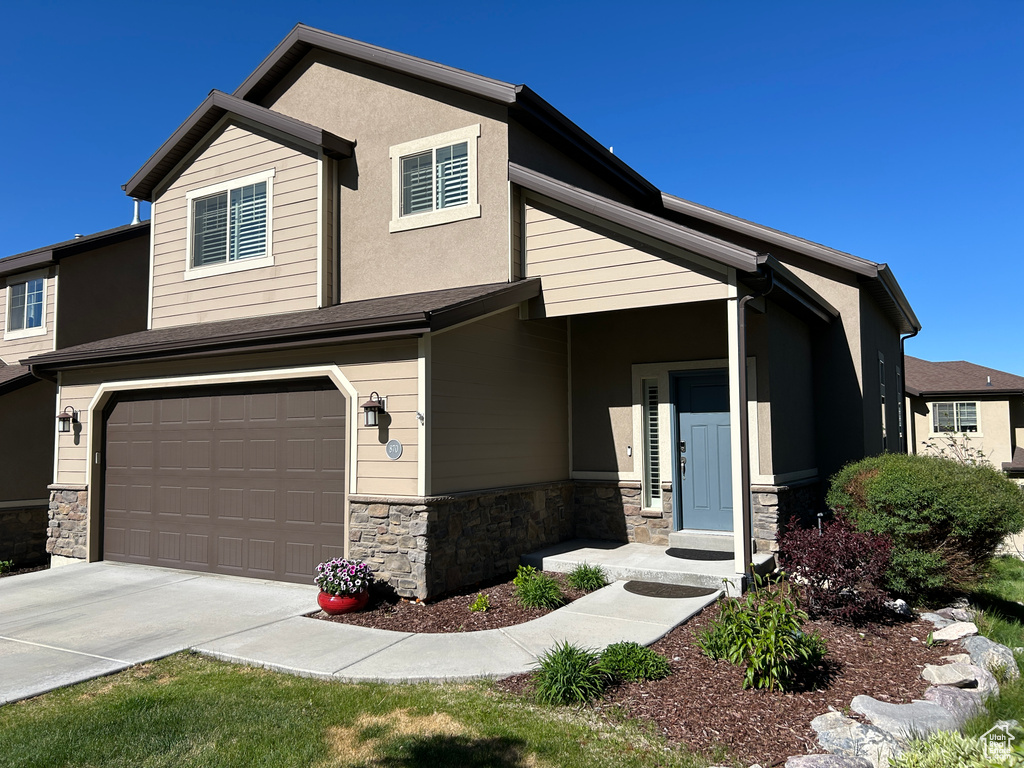 View of front of property with a garage, concrete driveway, and stone siding