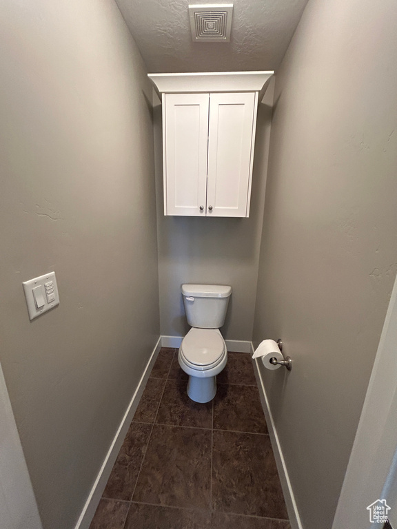 Bathroom featuring visible vents, baseboards, tile patterned floors, and toilet