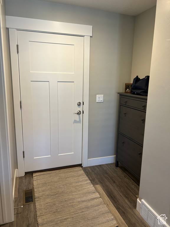 Doorway to outside featuring baseboards, dark wood-type flooring, and visible vents