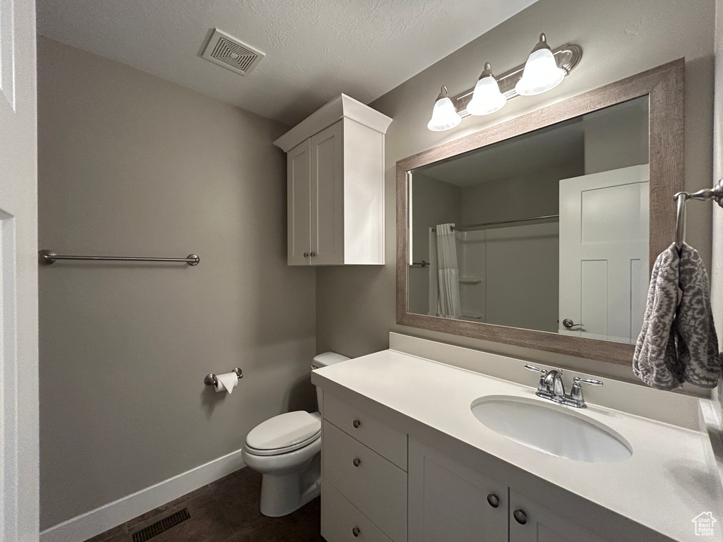 Full bath with baseboards, vanity, toilet, and visible vents