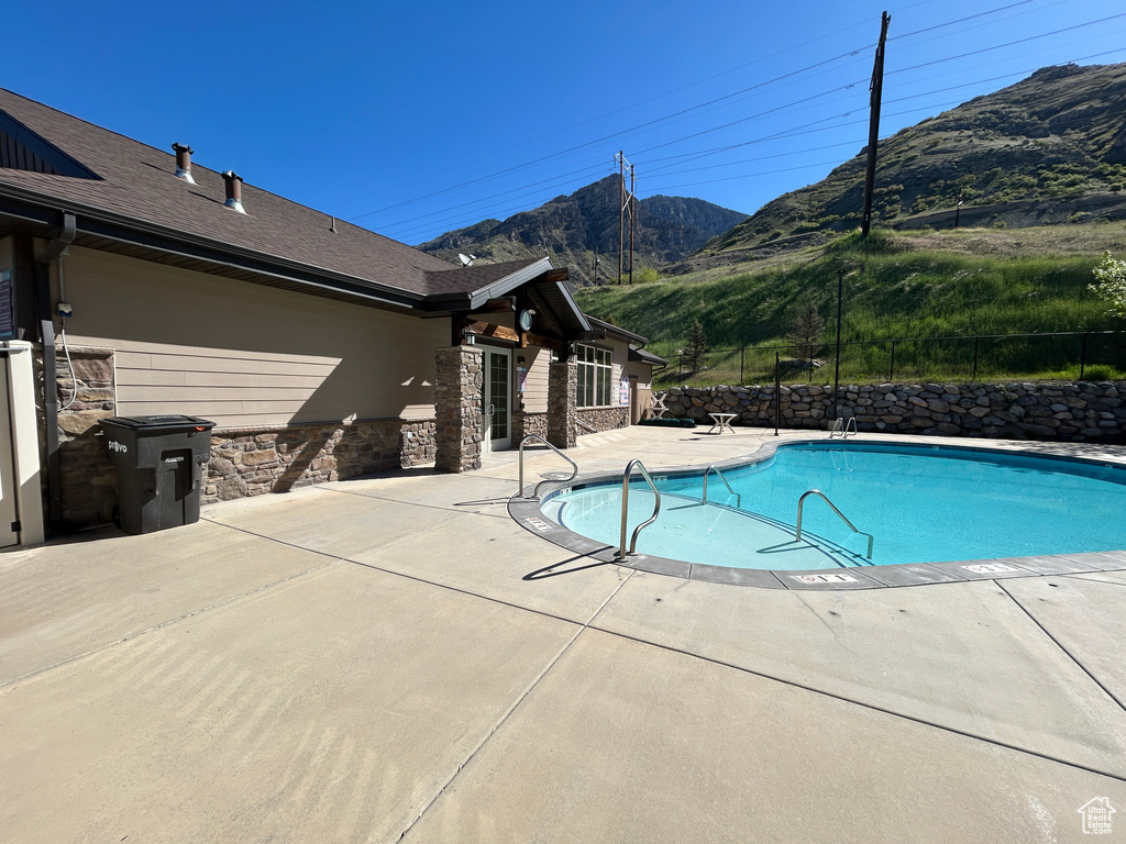 Community pool with a patio area, a mountain view, and fence