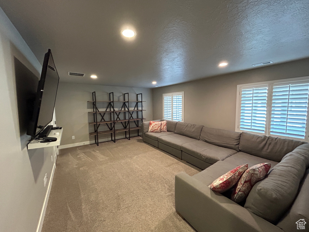 Carpeted living area with visible vents, recessed lighting, baseboards, and a textured ceiling