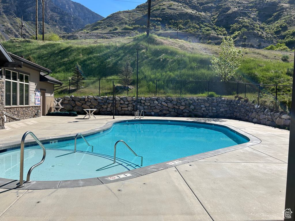 Community pool with fence, a mountain view, and a patio area
