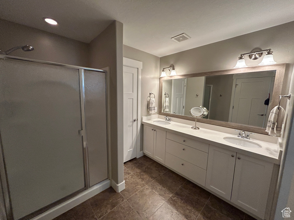 Full bath featuring visible vents, a sink, double vanity, and a shower stall