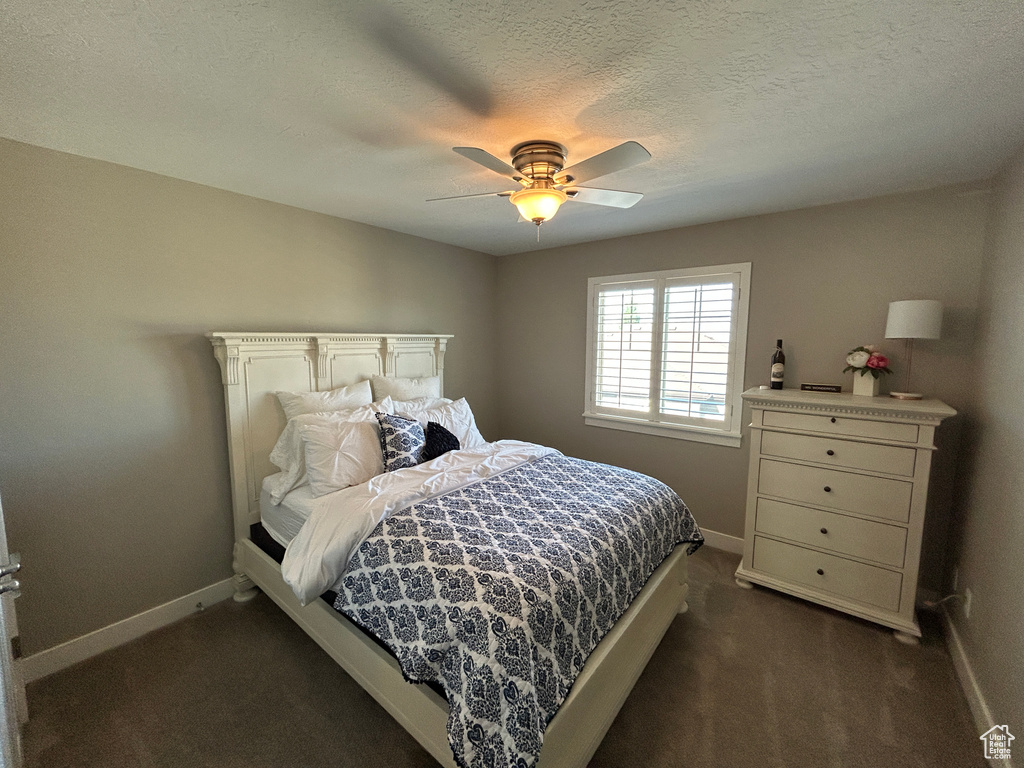 Bedroom with baseboards, ceiling fan, and dark colored carpet