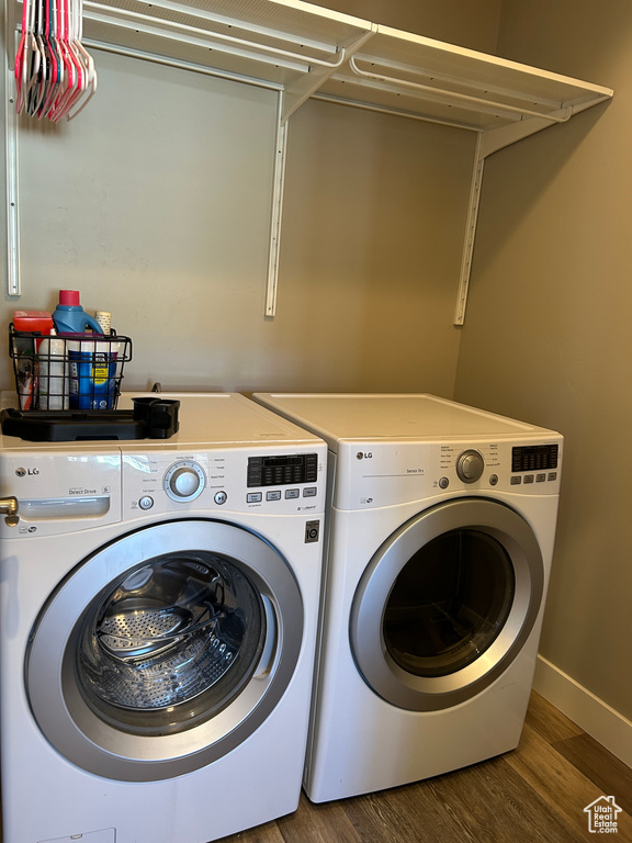Clothes washing area featuring separate washer and dryer, baseboards, laundry area, and wood finished floors