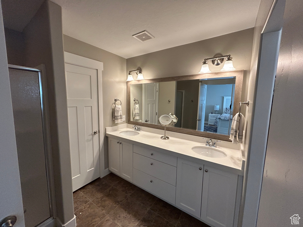 Ensuite bathroom featuring double vanity, a stall shower, a sink, and ensuite bath