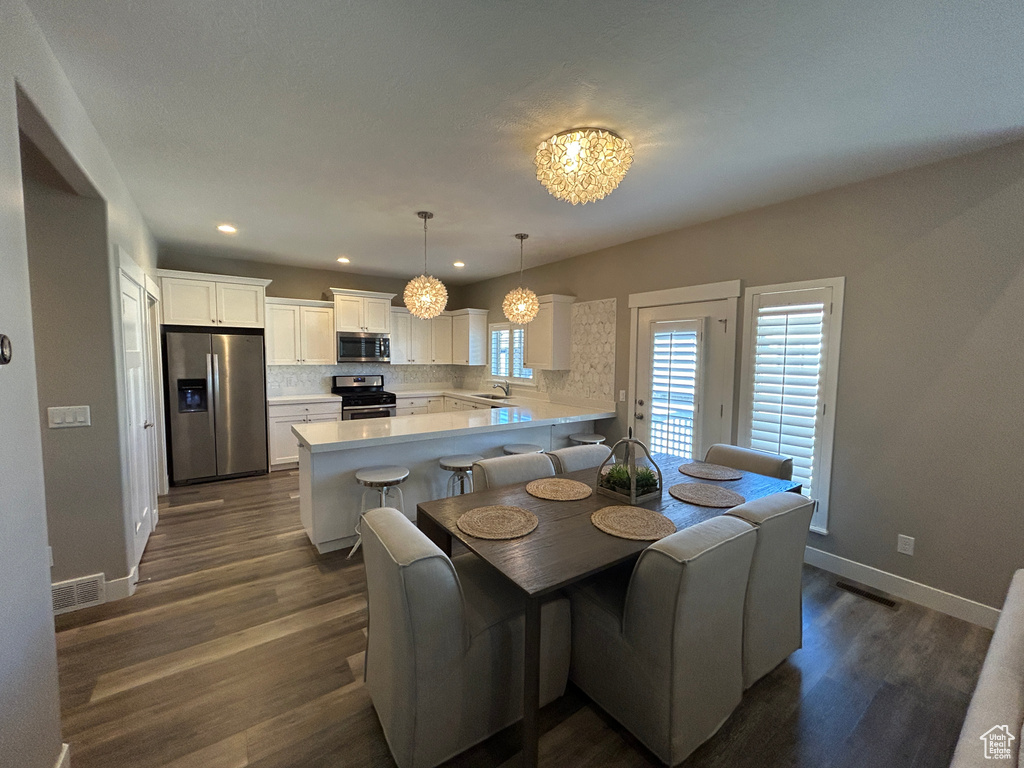 Dining area with visible vents, dark wood-style flooring, baseboards, recessed lighting, and a notable chandelier