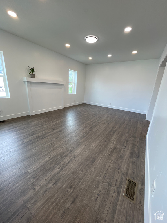 Unfurnished living room featuring recessed lighting, visible vents, baseboards, and dark wood-style floors