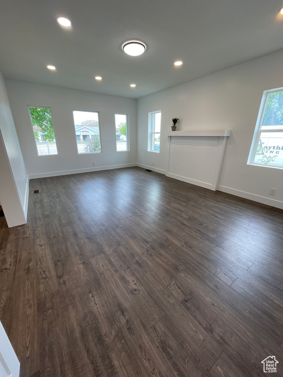 Unfurnished living room featuring dark wood-style floors and a healthy amount of sunlight