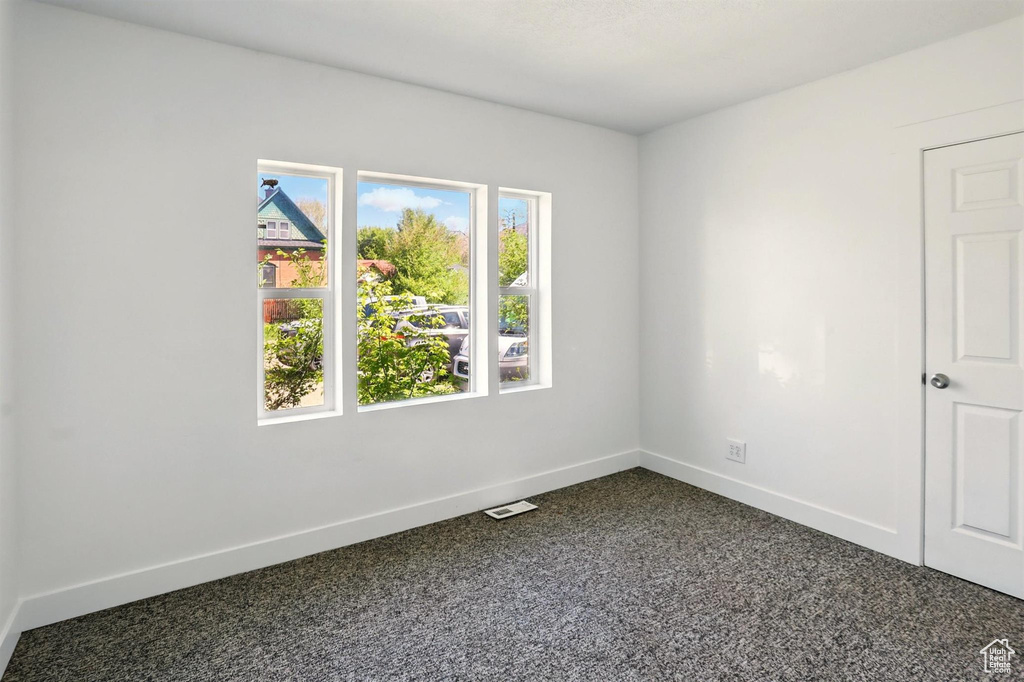 Empty room with dark colored carpet, baseboards, and visible vents