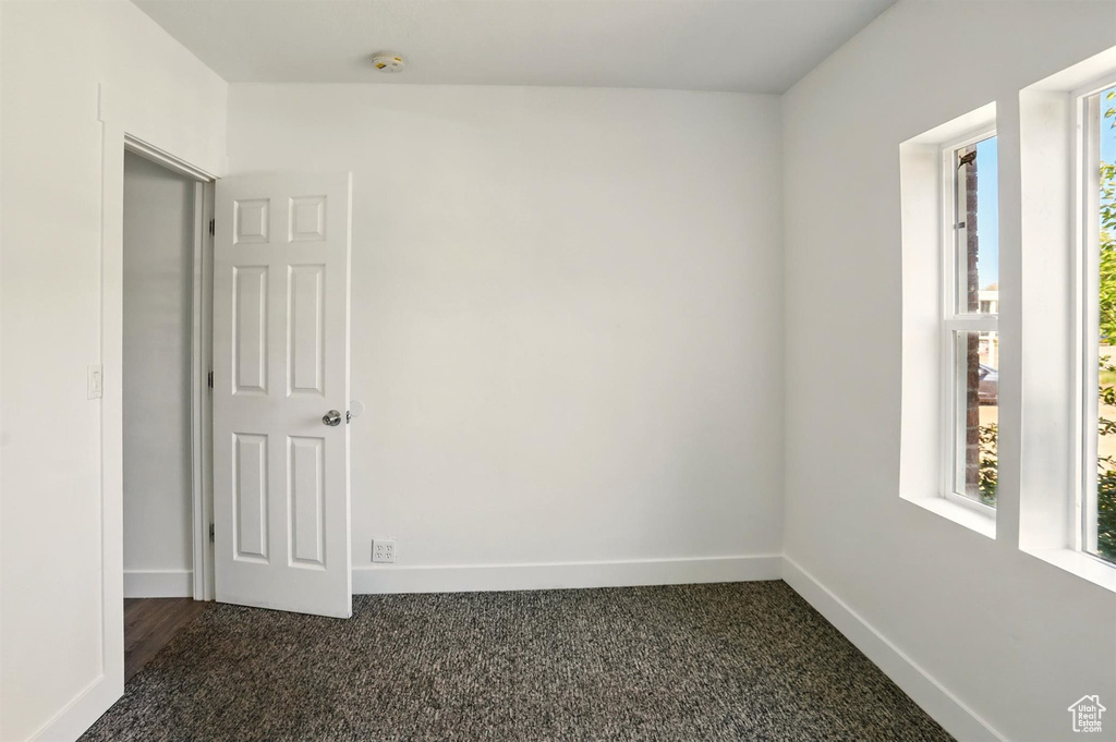 Unfurnished room with baseboards and dark colored carpet