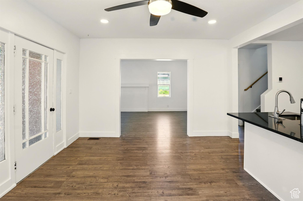Interior space featuring a sink, dark wood finished floors, stairs, a ceiling fan, and baseboards