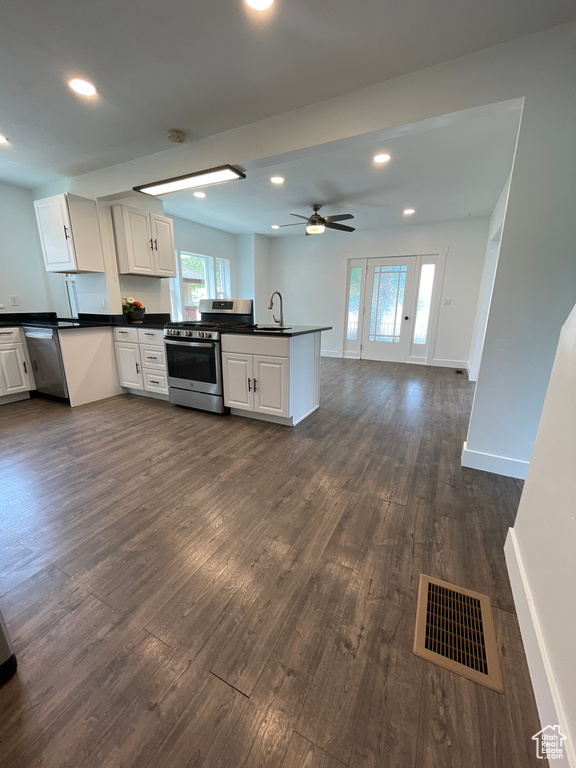 Kitchen featuring stainless steel range with gas stovetop, dark countertops, a peninsula, and visible vents