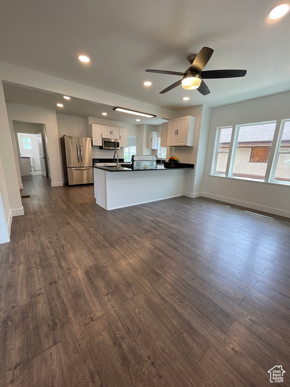 Kitchen featuring dark countertops, stainless steel appliances, white cabinets, and dark wood-type flooring
