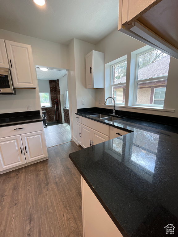 Kitchen with a sink, a healthy amount of sunlight, white cabinetry, dark wood-type flooring, and white microwave