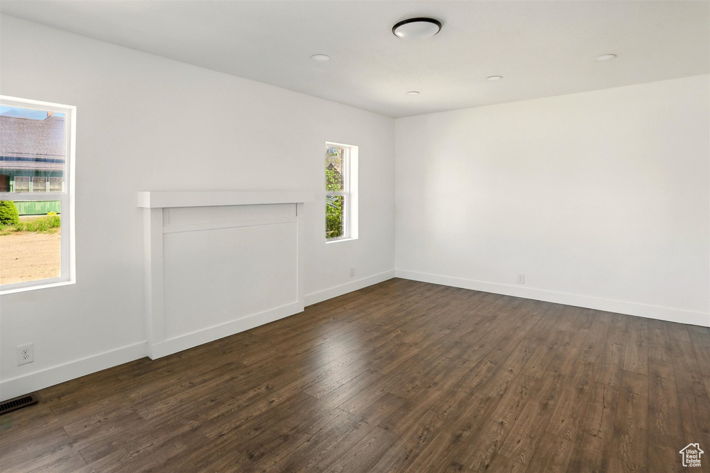 Unfurnished living room featuring dark wood-style flooring, baseboards, and visible vents