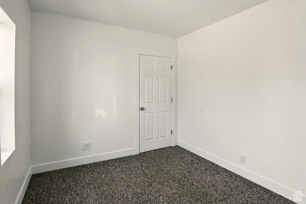 Unfurnished room featuring baseboards and dark colored carpet