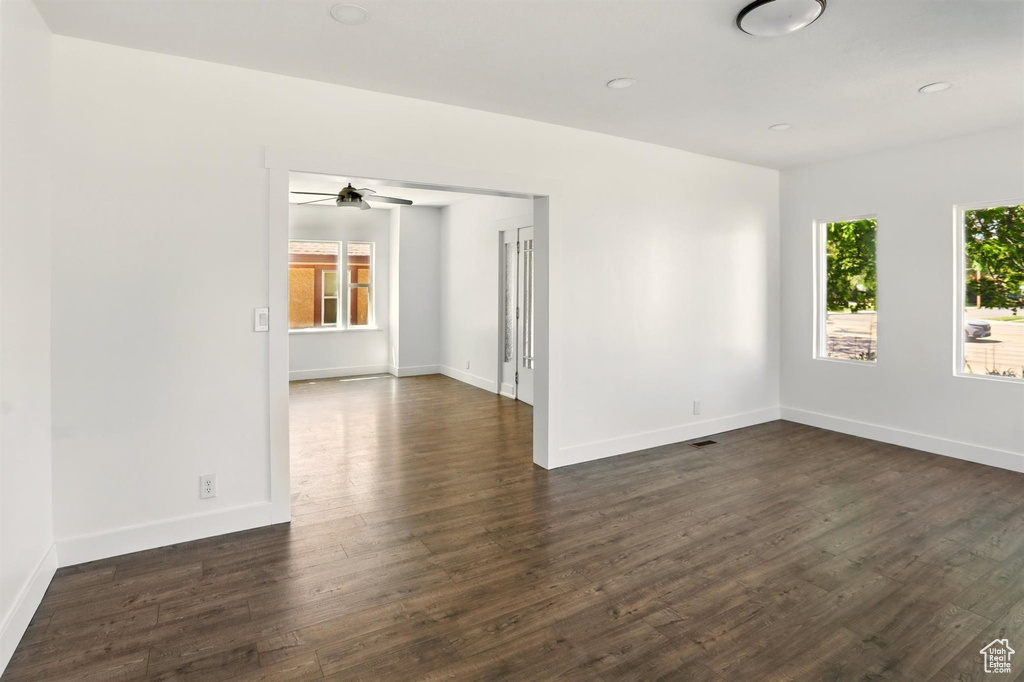 Unfurnished room featuring baseboards, dark wood-style flooring, and ceiling fan