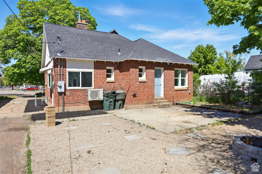 Rear view of property featuring fence, a shingled roof, brick siding, entry steps, and a chimney