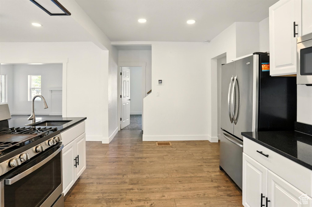 Kitchen with stainless steel appliances, white cabinetry, and a sink