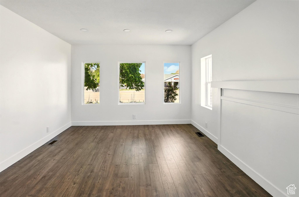 Empty room featuring baseboards, recessed lighting, dark wood-style floors, and visible vents