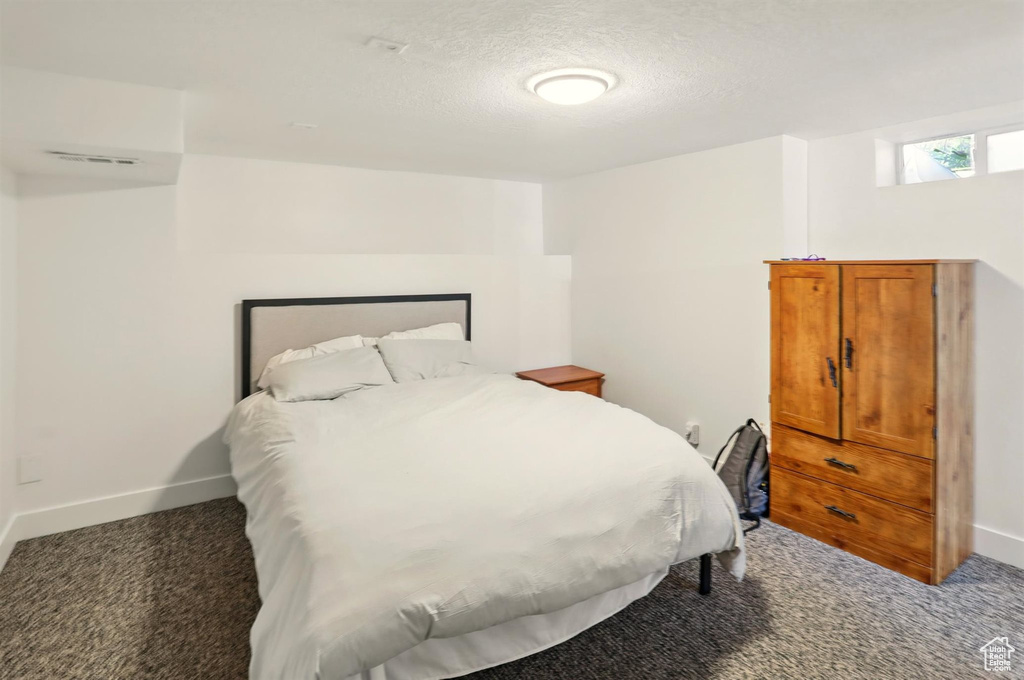 Carpeted bedroom featuring baseboards, a textured ceiling, and visible vents