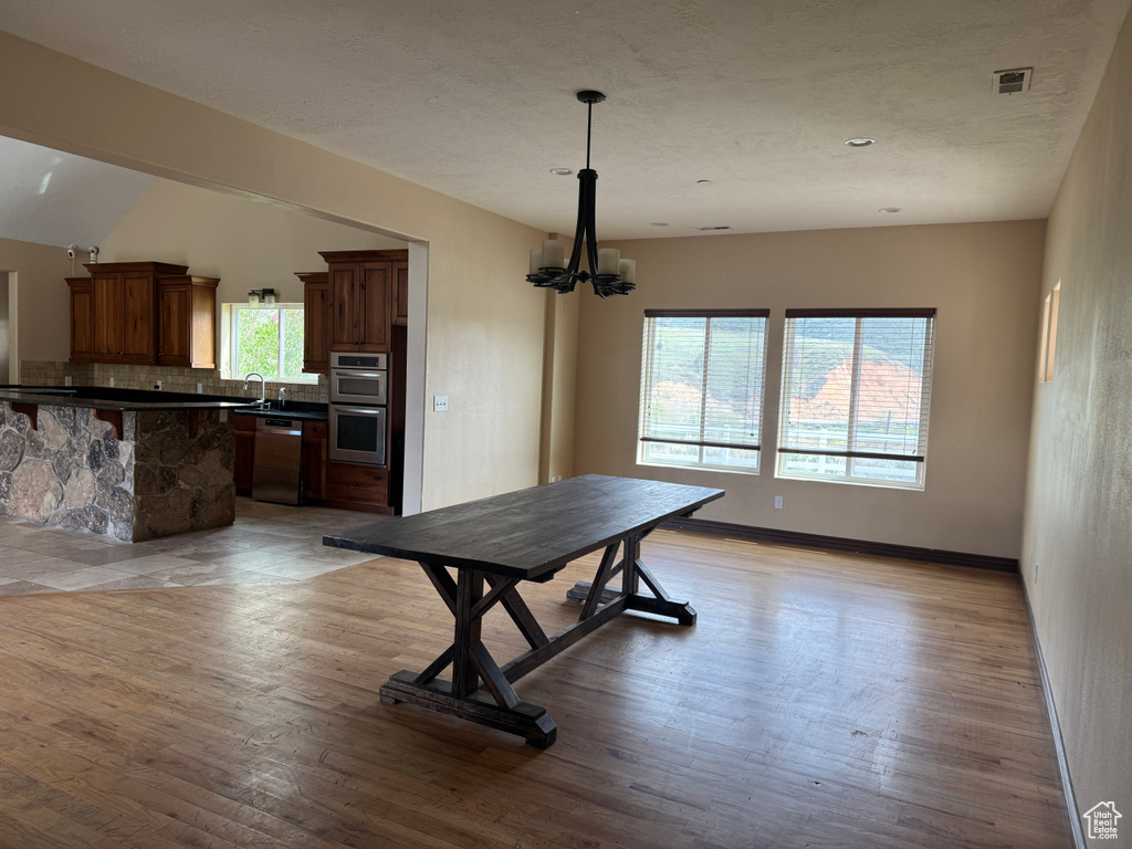 Dining room featuring a chandelier, light wood-type flooring, and baseboards