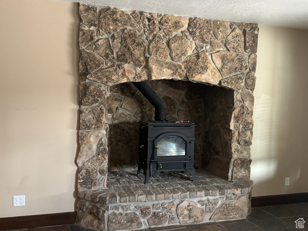 Detailed view of a wood stove, baseboards, and a textured ceiling