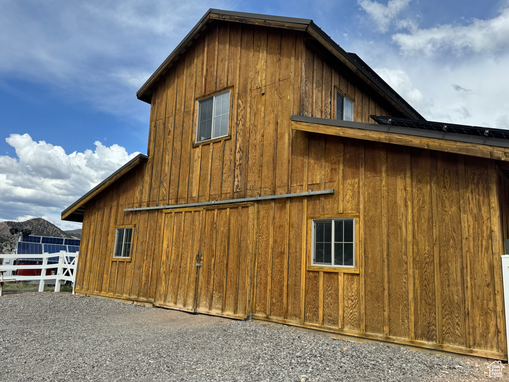 View of side of property with fence, board and batten siding, a barn, and an outdoor structure