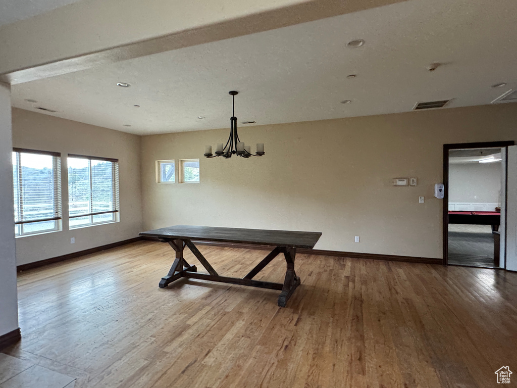 Unfurnished dining area with baseboards, wood finished floors, and a chandelier