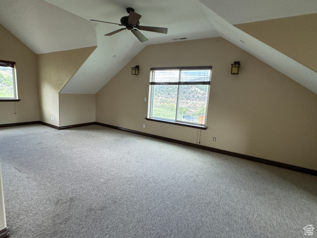 Bonus room with light carpet, lofted ceiling, healthy amount of natural light, and baseboards