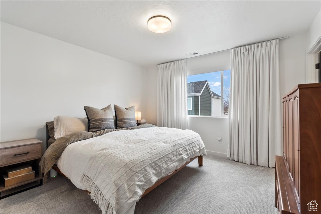 Carpeted bedroom featuring baseboards and visible vents
