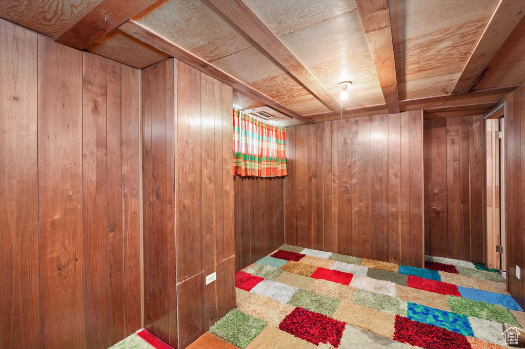 Finished basement with wooden walls, visible vents, and carpet floors