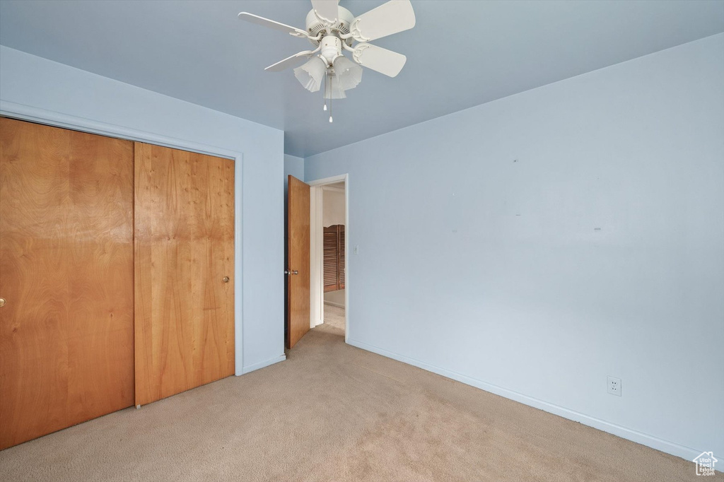 Unfurnished bedroom featuring a closet, carpet, ceiling fan, and baseboards
